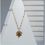 Gold-plated stainless steel leaf pendant on delicate chain, close-up view of women's jewelry accessory