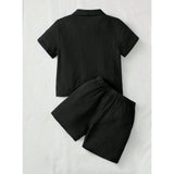 Black popcorn solid short sleeve shirt and shorts set for boys, collar neck and short sleeves, on a hanging rack