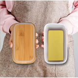{ "alt_text": "White ceramic butter box with bamboo lid, airtight storage container for fresh butter, kitchen countertop accessory" }
