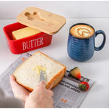{ "alt_text": "Red ceramic butter box with bamboo lid, airtight storage container for fresh butter, kitchen countertop accessory" }