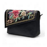 { "alt_text": "Black polyurethane crossbody sling bag with floral embroidery, adjustable strap, women's fashion accessory" }