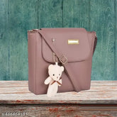 Stylish PU leather handbag with adorable teddy bear charm, perfect for women and girls. Free size, 2 compartments, solid pattern