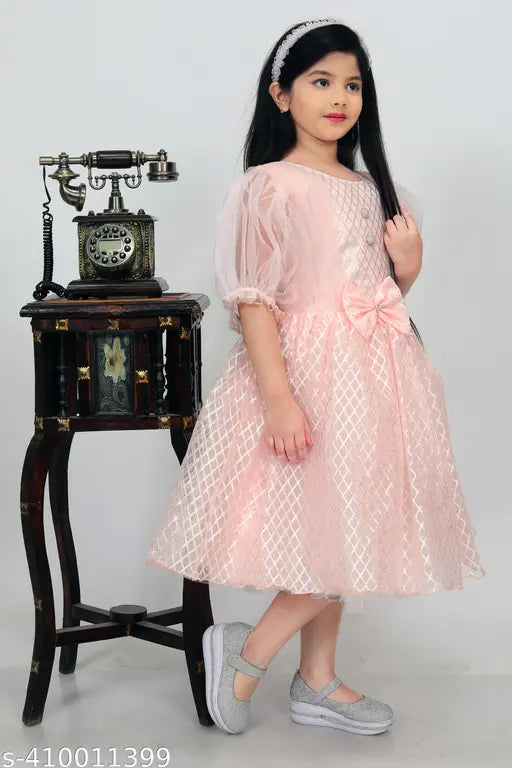 Light peach modal dress for girls, printed net, three-quarter sleeves. Soft, luxurious fabric with blush tones evoking nature's embrace. Indian craftsmanship