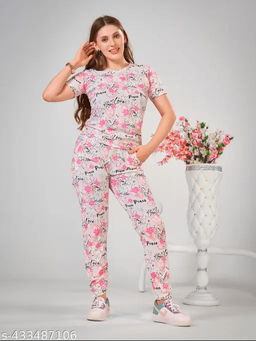 Pink printed cotton-blend night suit set for women, featuring top with short sleeves and ankle-length bottoms with pockets and drawstring waist, versatile for sleep, lounge, travel, yoga, or parties. Made in India