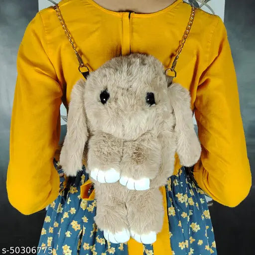 Yellow and brown plush rabbit with large eyes, held by person in a mustard yellow blouse with puffed sleeves