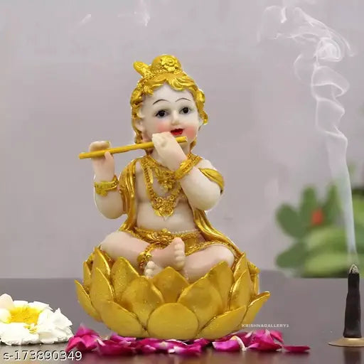 A golden polyresin figurine of Lord Krishna in a baby lotus pose, part of the Radha-Krishna love couple set, with a candle beside it. The statue is 6 inches tall and has a radiant appearance due to its polyresin material