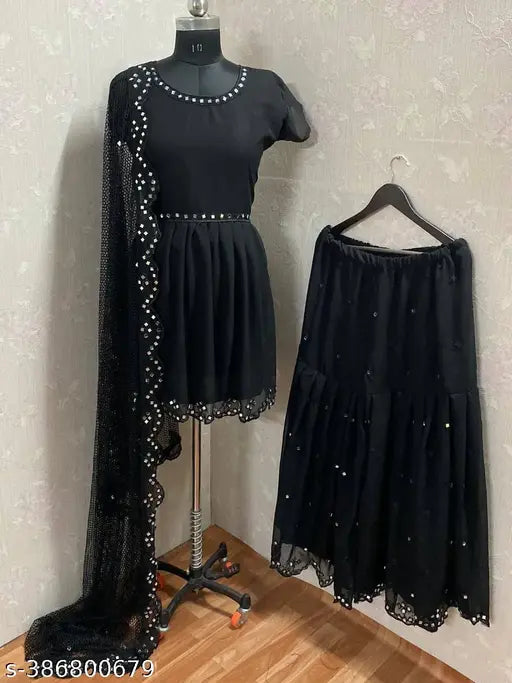 A mannequin showcasing a black ruffled dress with intricate detailing, and a matching skirt with fringes. The dress features an open back with beading details, suitable for festive wear