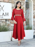 Red kameez with embroidery on the bodice and long sleeves, standing outside a building