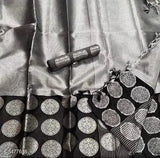 This is a close-up of an attractive Banarasi silk sari. The sari features intricate silver embroidery on a black background, giving it an elegant and luxurious look. The sari appears to be tied in the traditional pallu style, with one end draped over the shoulder and the other end hanging down freely