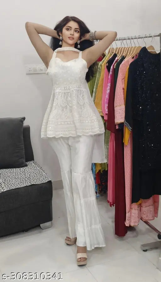 White lace sleeveless top with high slit side, paired with white pants