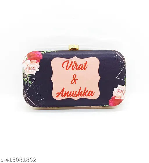 A small, black leather clutch with a floral pattern featuring rose and pussy willow motifs and a pink rectangular logo with text reading 'Virat & Anushka', designed for a photograph