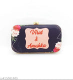 A small, black leather clutch with a floral pattern featuring rose and pussy willow motifs and a pink rectangular logo with text reading 'Virat & Anushka', designed for a photograph