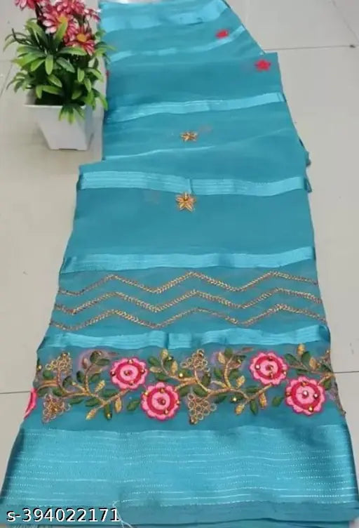 A long, teal blue cloth with gold sequin trim, and a few flowers sewn onto it