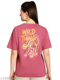 A woman wearing a large pink tee shirt with the words "Wild Things" on it, standing against a light background