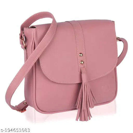 Pink faux leather sling bag with tassel accents, adjustable shoulder strap