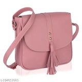 Pink faux leather sling bag with tassel accents, adjustable shoulder strap