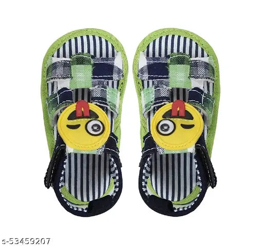The image features a pair of colorful children's sandals with blue, white, and red colors. Each sandal has a large emoji face on the side, which appears to be a sad or crying face. The design includes black straps that wrap around the ankles