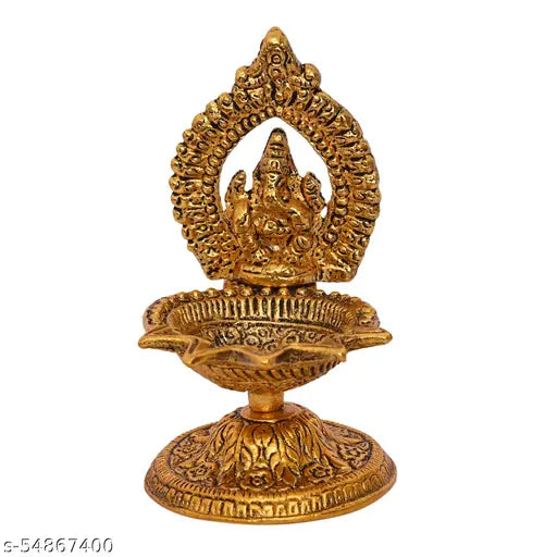A golden idol of Lord Ganesha on a stand, with a lit diya placed in front