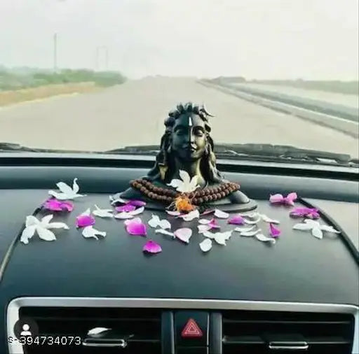 Black idol of Lord Shiva in car decoration, adorned with flowers and ribbon