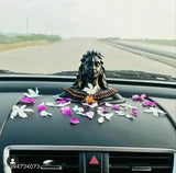 Black idol of Lord Shiva in car decoration, adorned with flowers and ribbon