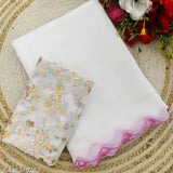 White saree with gold border and pink hem, presented on a bedspread