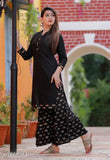 Black rayon kurta with sharara bottom, woman standing outside