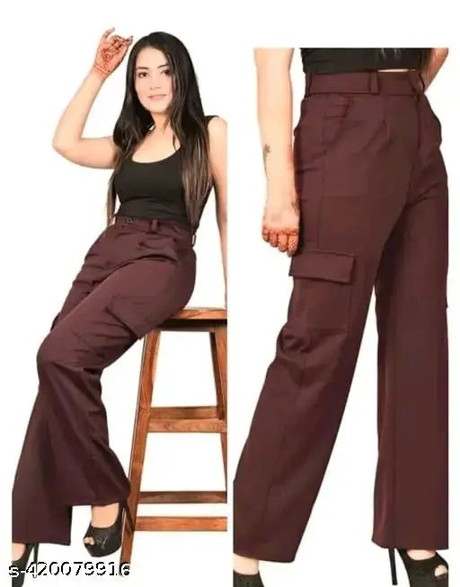 A woman posing in front of a white background, wearing brown high-waisted bell bottom trousers