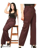 A woman posing in front of a white background, wearing brown high-waisted bell bottom trousers