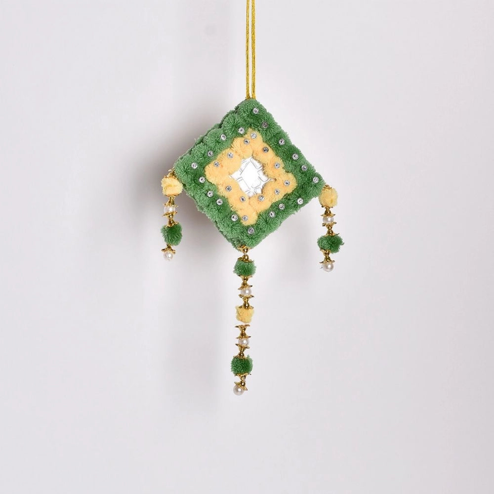 A decorative green and yellow pompom on a string, handmade wall art