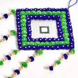 Handmade wall art with pompoms, navy blue background and green accents