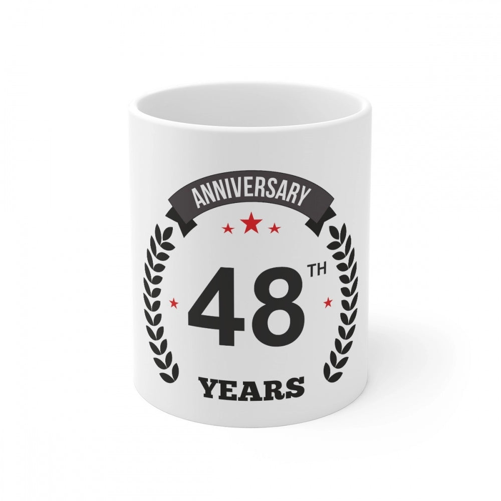 A white coffee mug with an anniversary print and a handle