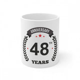 A white coffee mug with an anniversary print and a handle