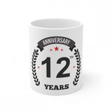 White ceramic coffee mug with a printed anniversary design and '12th' indicating it's for a 12th anniversary celebration