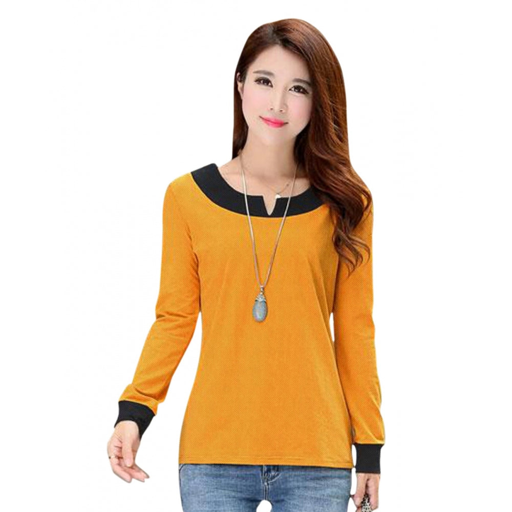 A woman wearing a yellow, long-sleeved top with an orange collar over a white turtleneck