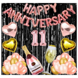Rose gold foil balloons with "11th Anniversary" decoration, champagne glass, black background.