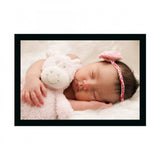 Baby wearing a pink bow, holding a stuffed animal, smiling, lying on a white surface