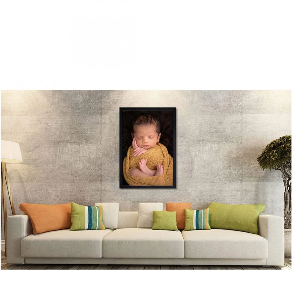 The image shows a multicolored baby photo painting with a rectangular frame displayed on a wall in front of a couch
