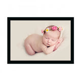 Multicolor baby photo painting of sleeping newborn with floral hairband and pink rose headband, framed within a black photo frame with glass