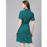 The dress is blue with white polka dots. It has short sleeves and is above knee length. The material appears to be a synthetic fabric, likely polyester