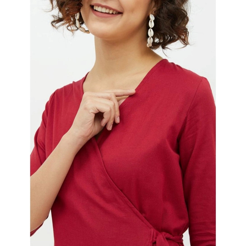The image displays a woman wearing a sleeveless maroon dress. The dress appears to be made of cotton material and features a wrap design that covers the upper body, leaving the hands exposed. It reaches just above her knees, suggesting a midi length style