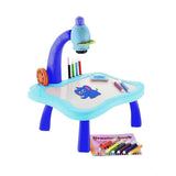The table is a child's drawing station with a projector. It has a blue base, various colored pencils on it, and a small book