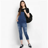 A woman wearing blue denim overalls, paired with white sneakers and carrying a black backpack