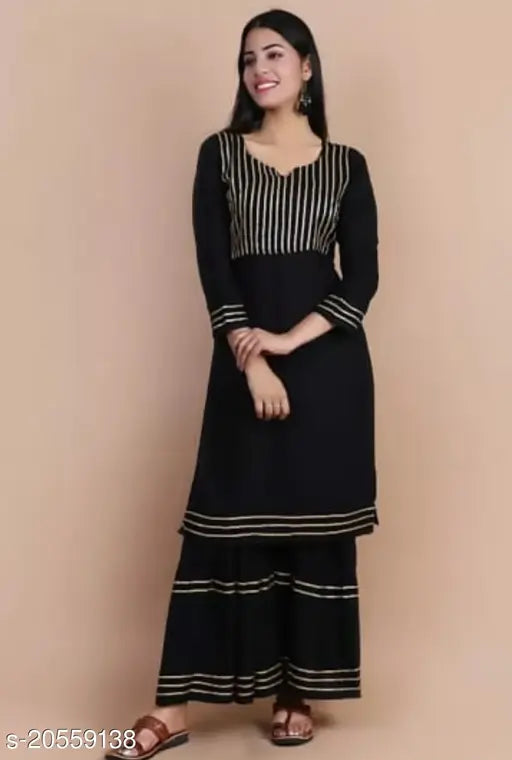 A black and beige kurta set with long sleeves, standing model against a neutral background