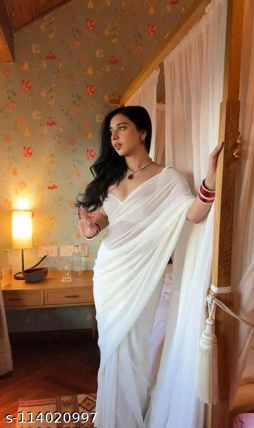 Serene woman wearing white Georgette saree, standing on porch