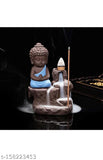 This is a decorative showpiece featuring a monk Buddha with a backflow cone incense holder. The statue of the Buddha appears to be crafted from a polished stone and has an intricate design, sitting on top of the incense holder. The holder is positioned in front of the Buddha, suggesting that it holds incense cones. There are no visible texts or branding on the statue or the incense holder