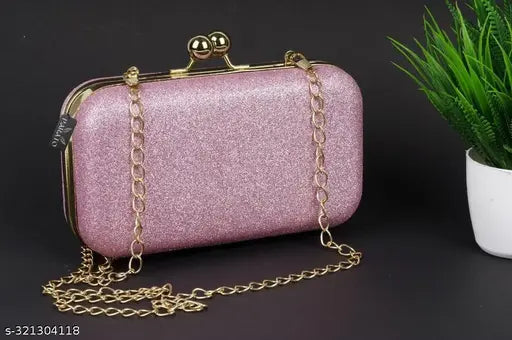A pink clutch with a chain strap in front of a plant, suitable for party wear