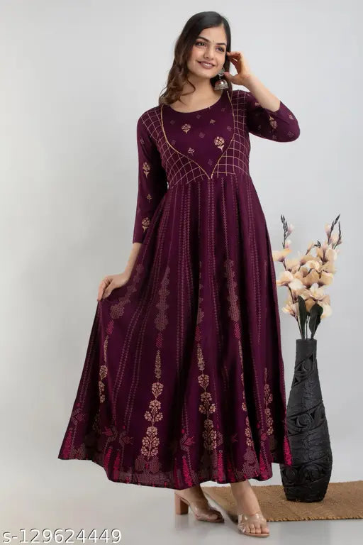 A woman wearing a long purple kurta with embroidery and standing next to a plant