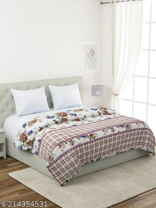 White and red floral bedspread with a blue pattern on a double-sized bed, designed by Nivasam, featuring an ultrasonic comforter