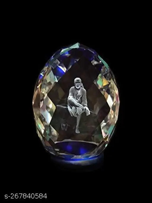 The image shows a large, clear crystal shaped into a human figure with dark details. It is set against a black background and has intricate designs throughout its surface