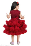 The image is of a young child standing and wearing a red, fluffy ruffle dress with puffy sleeves